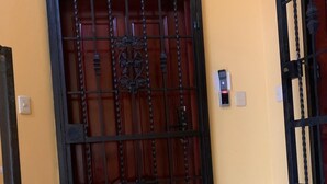 A closed metal gate with a decorative design, a yellow wall, and a tiled floor.