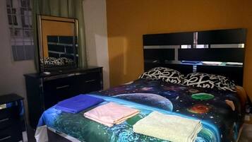 Une chambre à coucher comprenant un lit, une commode, un miroir, un ventilateur de plafond et un appareil de climatisation.