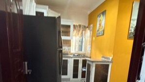 A kitchen with marble flooring, a refrigerator, cabinets, and a sink.