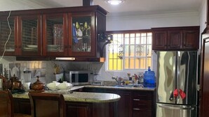 A kitchen with wooden cabinets, a stainless steel refrigerator, a microwave, and a dining area with chairs and a table.