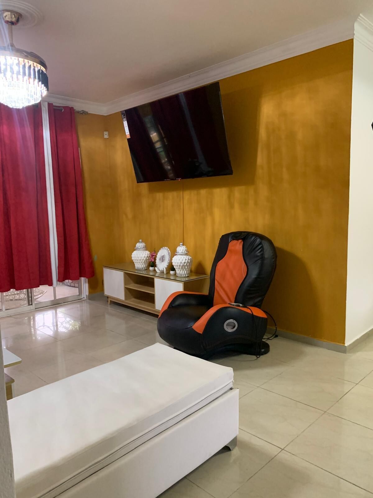 A living room with a sofa, a massage chair, a TV, and a cabinet with decorative items.