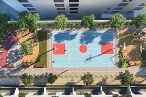 An aerial view of a residential area with a basketball court, playground, and surrounding greenery.