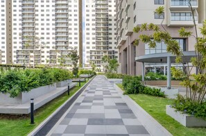 Un edificio residencial con un sendero central, áreas verdes y un diseño arquitectónico moderno.