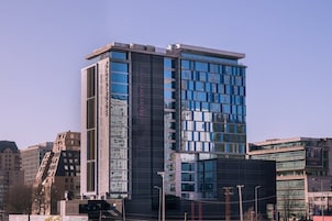 Un hotel moderno con fachada de vidrio, un cartel vertical llamativo y un techo plano.