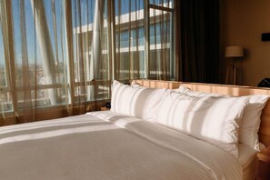 A hotel room with a bed, a window with sheer curtains, and a lamp on a bedside table. - Hotel Costanera Concepcion (Concepción)