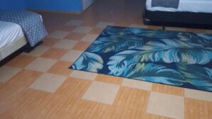 Ein Zimmer mit Schachbrettmuster Boden, einem Bett mit gemustertem Überwurf, einer Tür und einem Fenster.