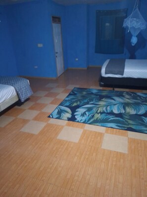 A room with a checkered floor, a bed with a patterned bedspread, a door, and a window.