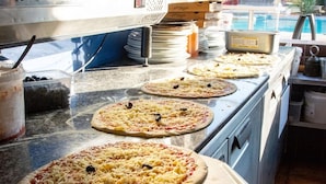 Una cocina con varios hornos de pizza, ingredientes para pizza y cajas de pizza.