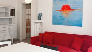 A red sofa, a white cabinet, and a painting of a sunset. - 5 minutes from milan central station- 3 minutes from piazza repubblica- comfort (Milano)