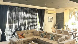 A modern living room with a sectional sofa, a round coffee table, and a black rug. - Modern Penthouse Overlooking Pool (Pyla)