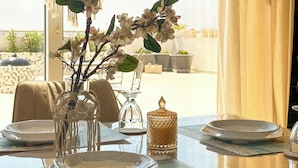 A dining table with a vase of flowers, a glass candle holder, and a decorative jar. - Modern Penthouse Overlooking Pool (Pyla)