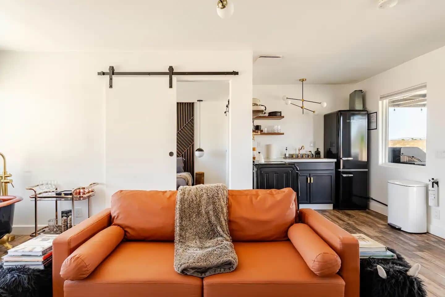 En moderne stue med en sofa, et sofabord og et køkken i baggrunden.