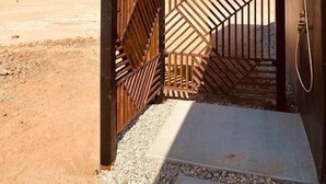 A desert landscape with a building featuring a metal gate and a shower. - DILIM - Designer Desert Retreat (Homestead Valley)