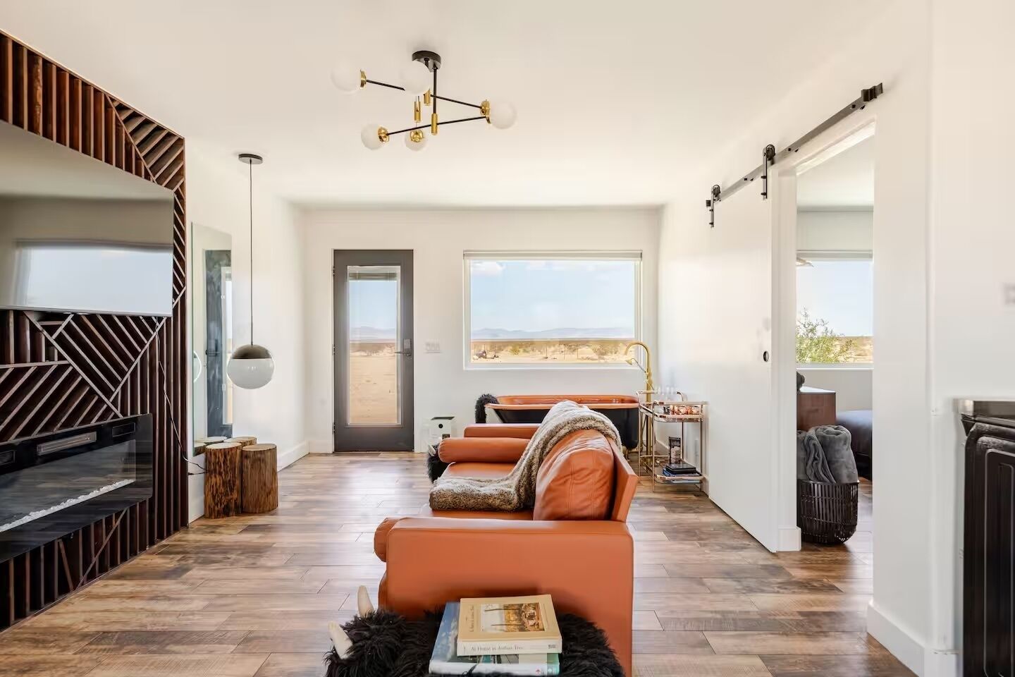 Ein modernes Wohnzimmer mit Kamin, einem großen Fenster mit Blick auf die Wüste und einer gemütlichen Sitzecke.