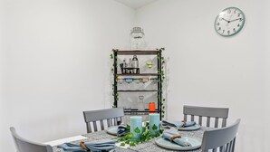 Une table à manger dressée avec des assiettes, des serviettes et des bougies, entourée de chaises.