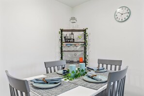 Ein Esstisch mit Tellern, Servietten und Kerzen, umgeben von Stühlen.