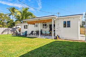 A single-story house with a covered patio, a fenced backyard, and a palm tree in the background. - 3BR/2BA - Modern Coastal Retreat-  Near Beach, Dining, Shops (Oakland Park)