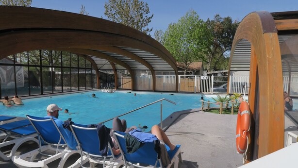 Zona de piscina con sillas de descanso, un flotador salvavidas y una sección cubierta con vistas a la piscina.