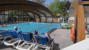 Un espace piscine comprenant des chaises longues, une bouée de sauvetage et une zone abritée d’où l’on peut admirer la piscine.