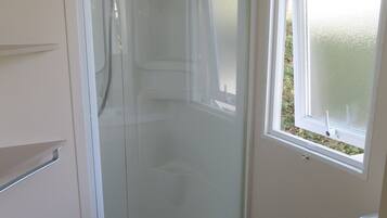 Une salle de bain avec une douche à parois de verre, une baignoire et une fenêtre.