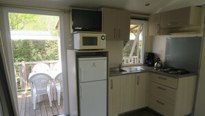 Una cocina compacta con refrigerador, microondas, estufa y lavamanos.