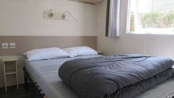 Une chambre à coucher comprenant un lit, des tables de chevet, une fenêtre et un luminaire fixé au mur.