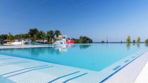 Una piscina azul cristalina con marcas de carril, un tobogán y vista al océano.
