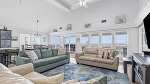 A spacious living room with a high ceiling, large windows, and a ceiling fan. - Catch & Release ~ Bay Front ~ Sleeps 12 (Dauphin Island)