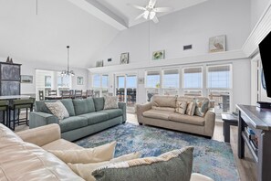 A spacious living room with a high ceiling, large windows, and a ceiling fan. - Catch & Release ~ Bay Front ~ Sleeps 12 (Dauphin Island)