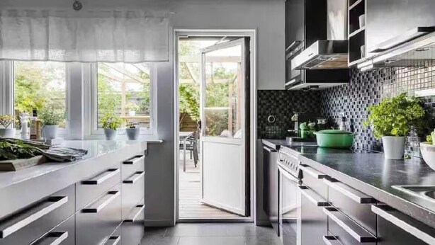 A modern kitchen with a sliding door to a patio, built-in cabinets, and a black backsplash. - Bright house near beach & center + free parking (Bunkeflostrand)