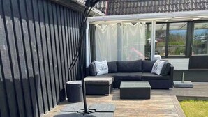 A deck with a sofa, lounge chairs, and a table. - Bright house near beach & center + free parking (Bunkeflostrand)