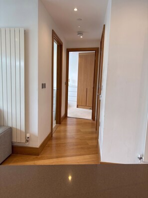 Ein Flur mit Holzboden, einem Heizkörper und einer Tür zu einem weiteren Zimmer.