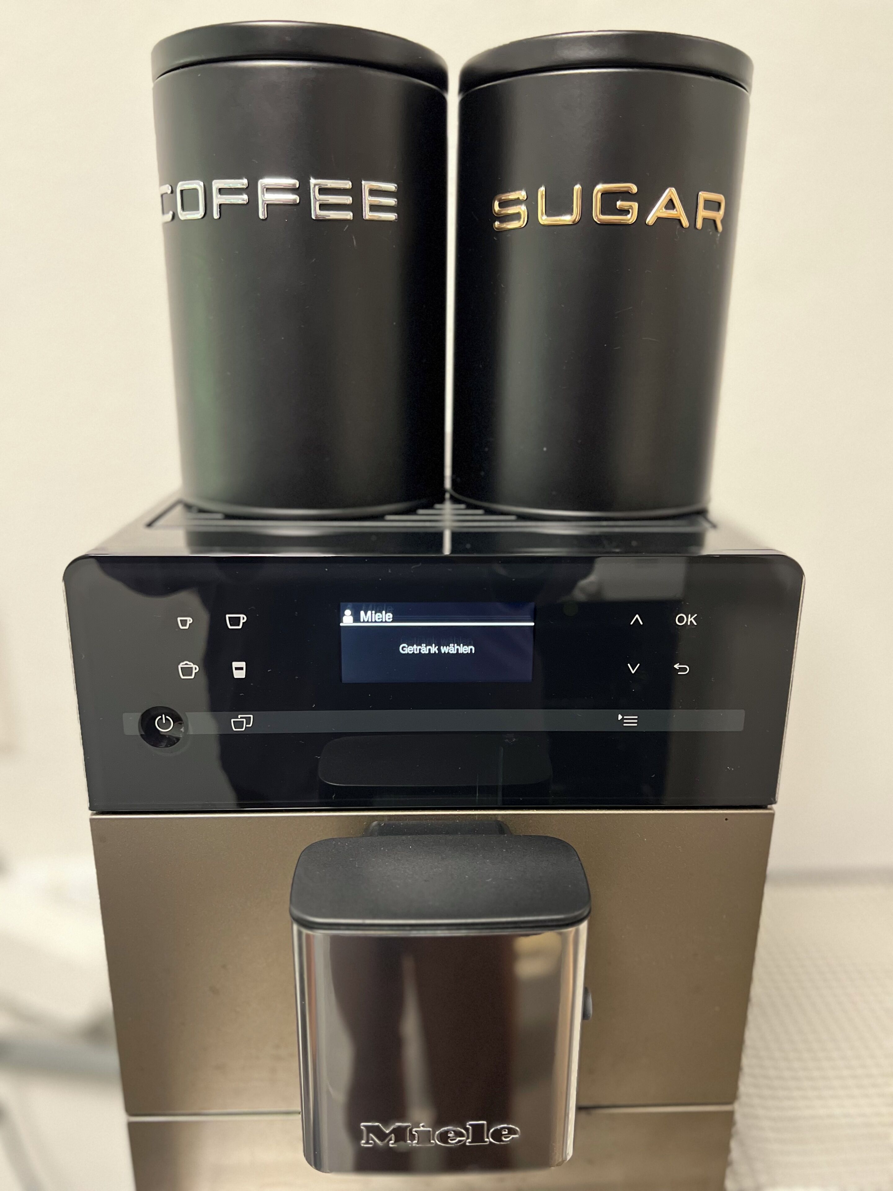 En kaffe- och sockerautomat med en digital display och varumärket ”Miele” på framsidan.