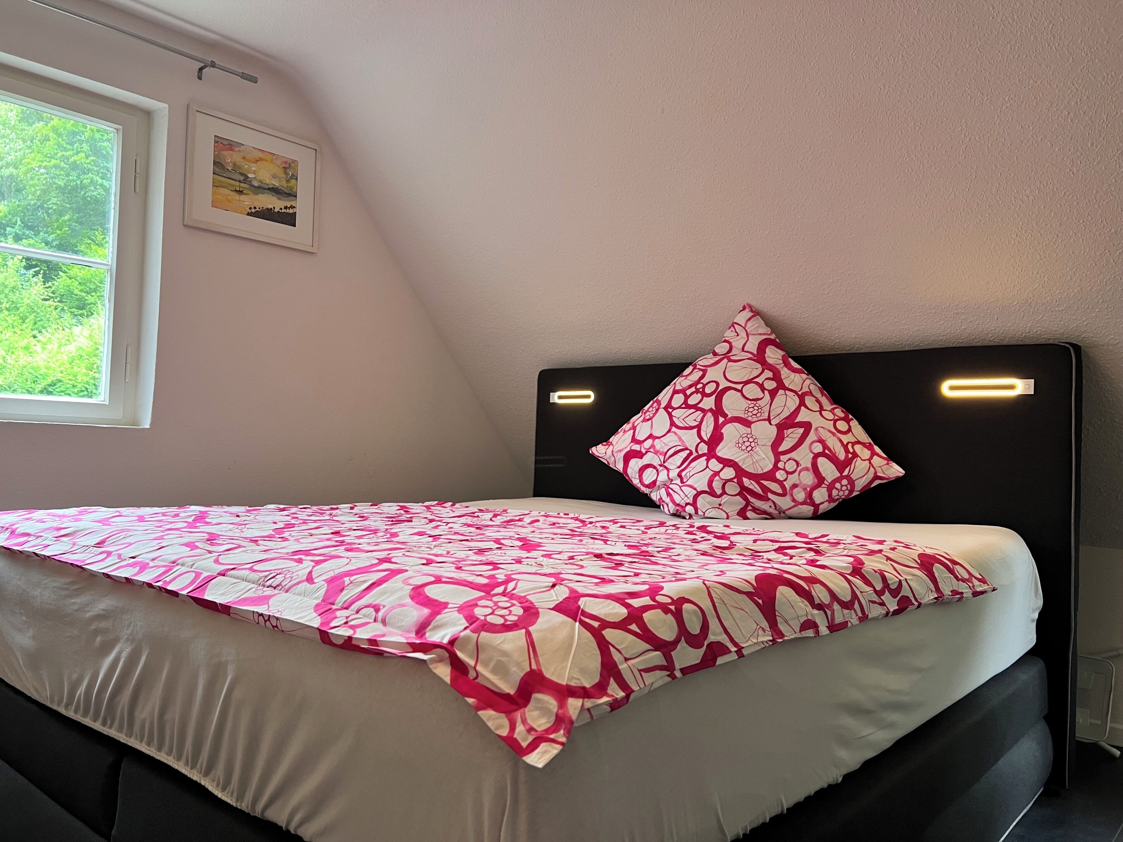 Une chambre à coucher avec un lit, une fenêtre et un tableau au mur.