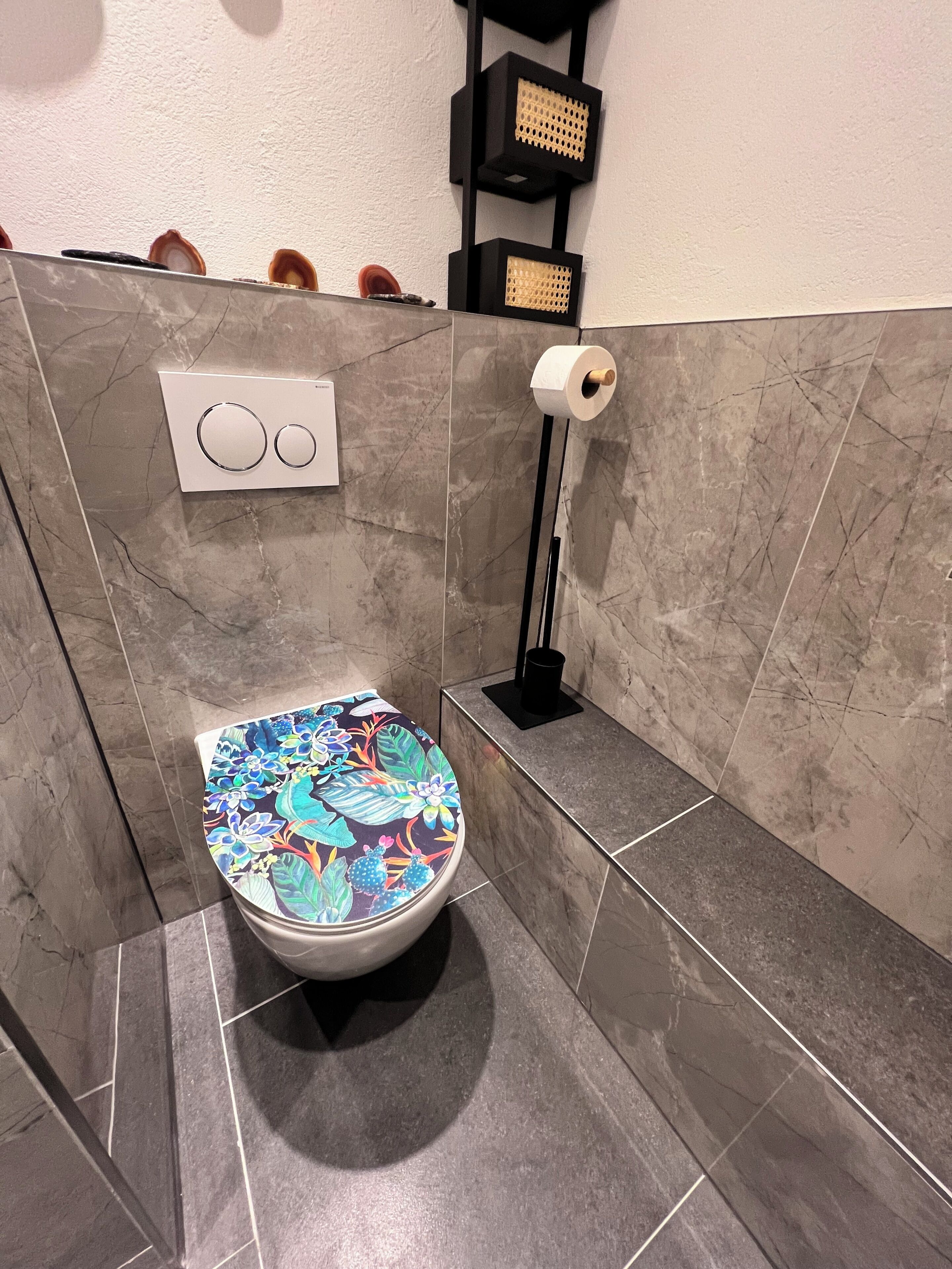Une salle de bain équipée de toilettes, d’un porte-rouleau de papier toilette et d’un porte-serviettes.