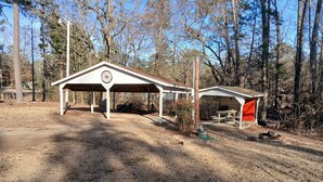 A covered pavilion with a wheel symbol, a smaller adjacent structure, and a dirt ground.