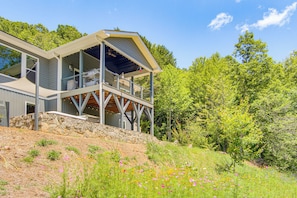 A modern house with a large deck, stone foundation, and surrounded by lush greenery. - Mtn-View Retreat in Asheville: Great for Groups! (Asheville)