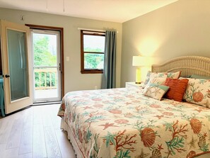 Ein Schlafzimmer mit Bett, Nachttisch, Lampe, einem Korbschlafbrett und einem Fenster mit Vorhängen.