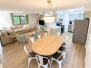 Un salon moderne comprenant un canapé, un téléviseur, une table à manger et des chaises.