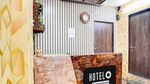 A reception desk with a 'HOTELO' sign, a clock, and a door. - Classic With Balcony Hotel SKR (Varanasi)
