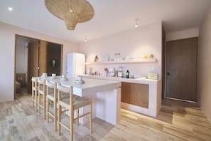 A modern kitchen with a central island, bar stools, and a hanging light fixture. - Tulum Jungle Oasis (Tulum)