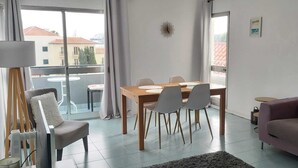 Un soggiorno moderno con zona pranzo, divano e balcone con vista sugli edifici.
