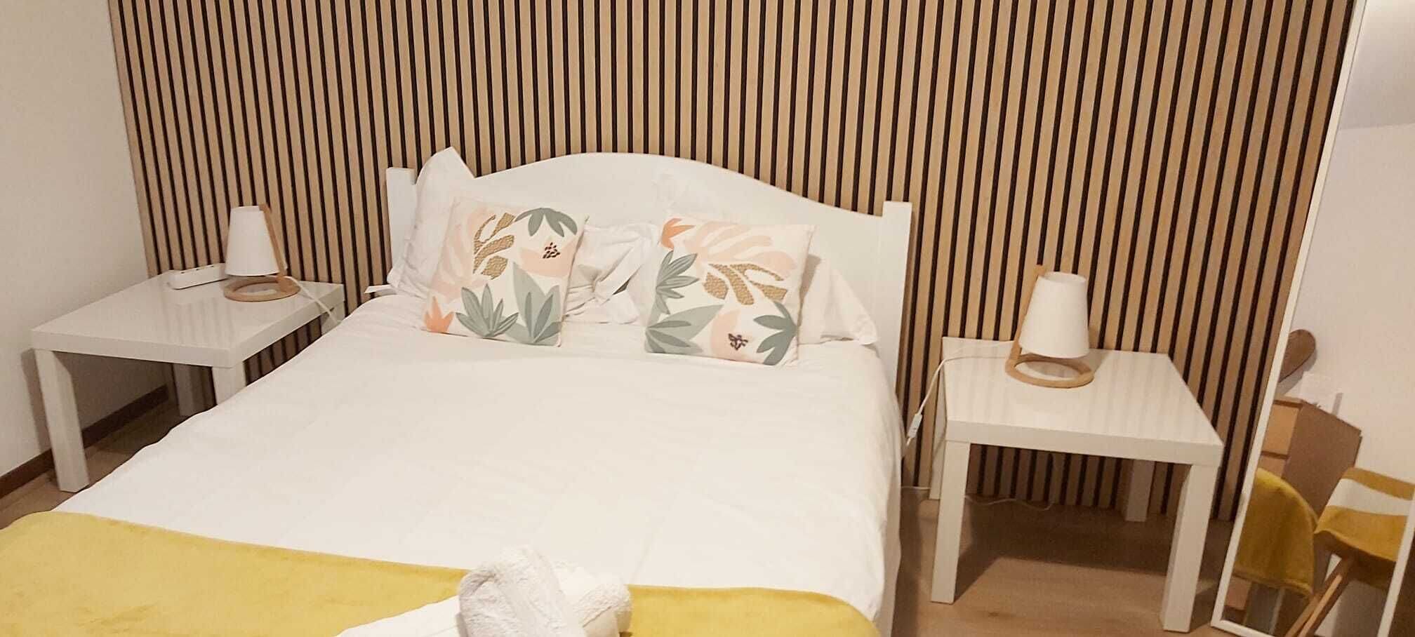 A bed with a white headboard, two bedside tables with lamps, and a yellow throw blanket.