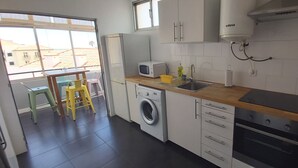 Una cucina compatta con lavatrice, forno a microonde, lavandino e forno.