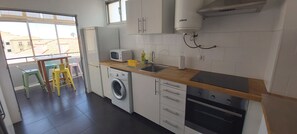Eine kleine Küche mit Waschmaschine, Mikrowelle, Spüle und Backofen.