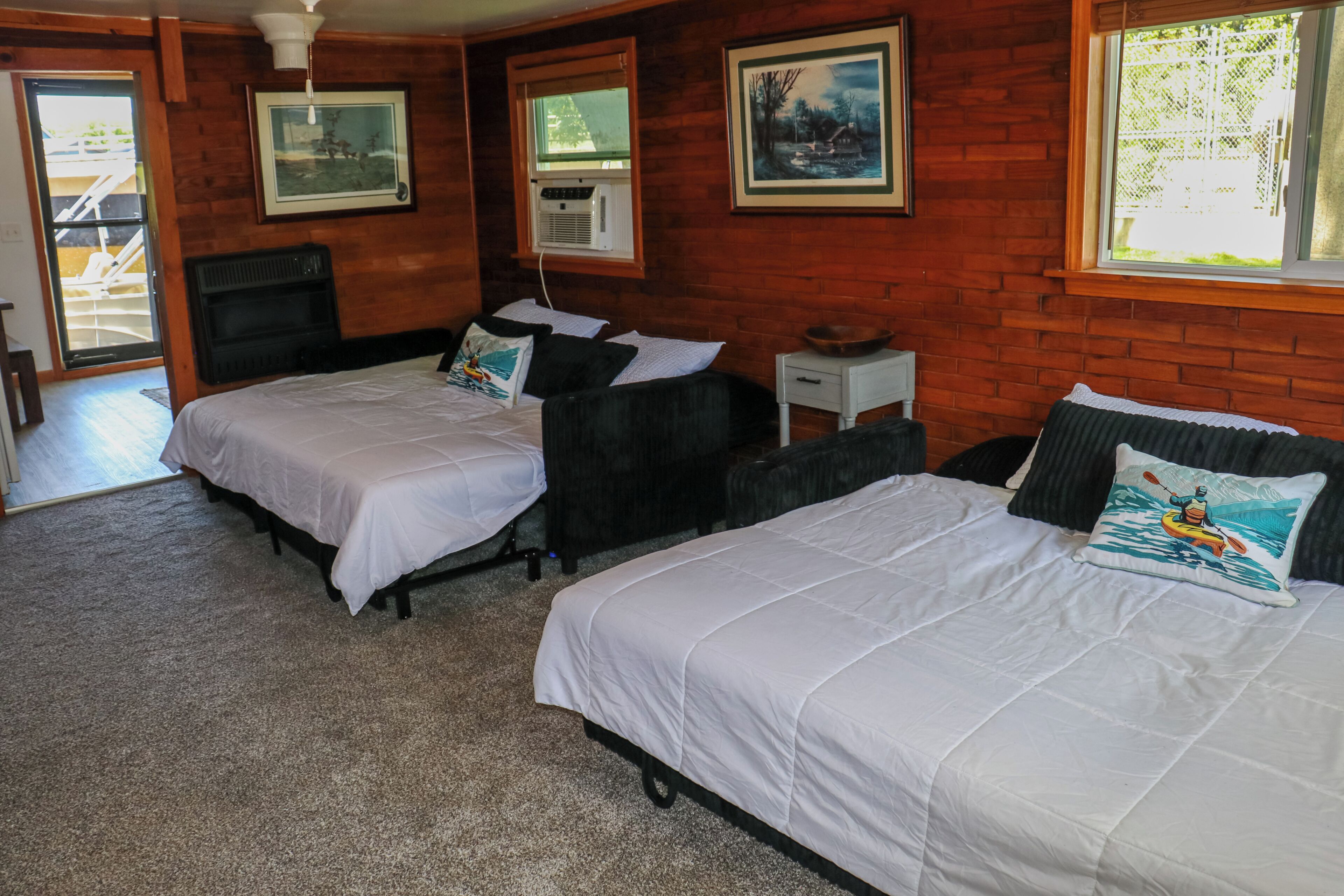 Une chambre d’hôtel avec deux lits, une petite table, une fenêtre et une porte donnant sur un balcon.