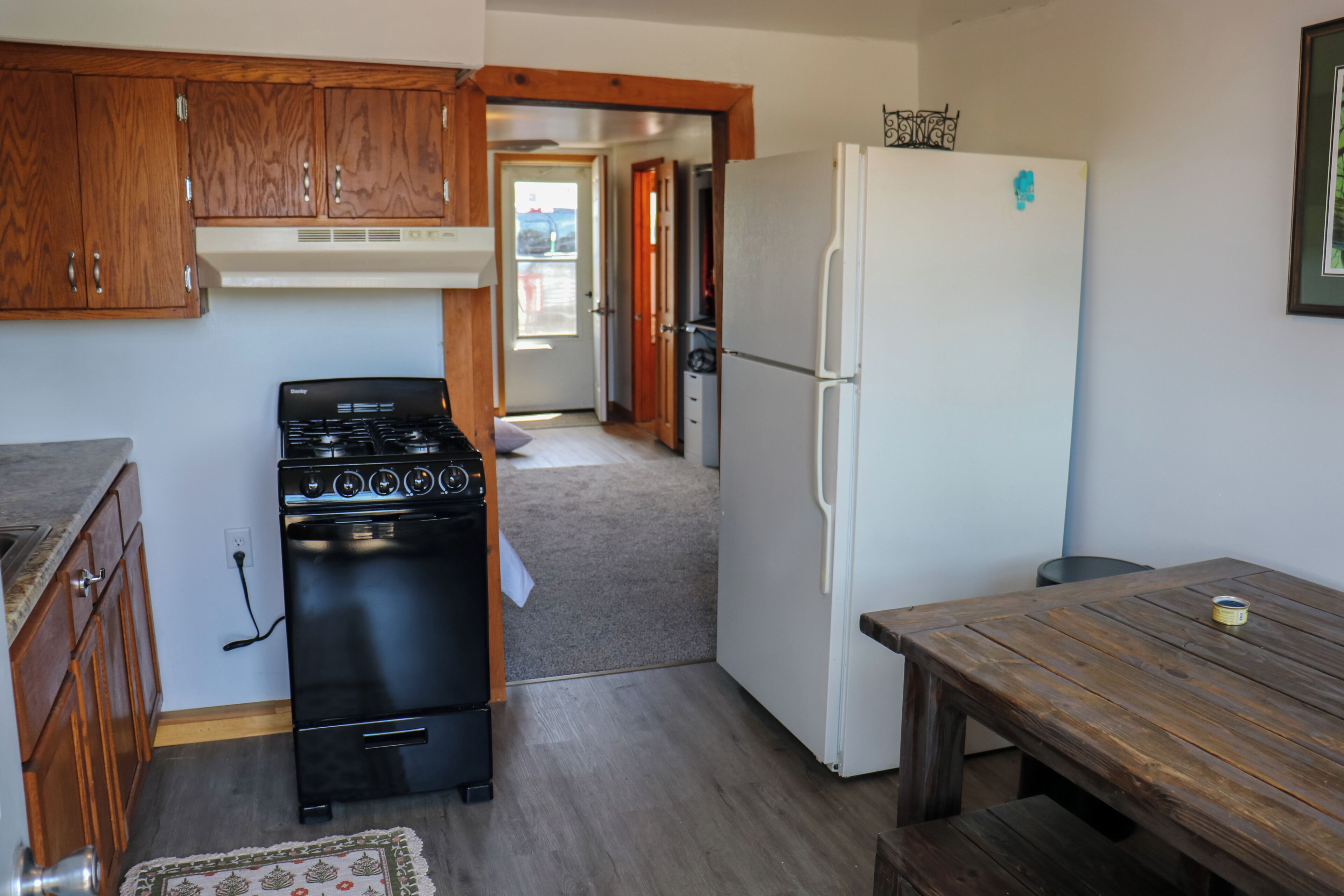 Une cuisine avec des meubles de rangement en bois, une cuisinière, un réfrigérateur et une table en bois.