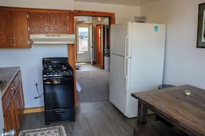 A kitchen with wooden cabinets, a stove, a refrigerator, and a wooden table.