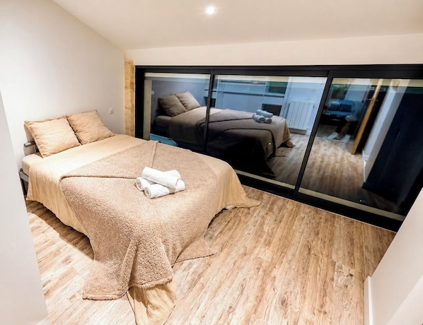 A bedroom with a large bed, a window, and a view of another room.