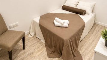 A small, neatly arranged room with a single bed, a chair, and a small table.